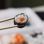 Food Aesthetics - Close-up of sushi roll with chopsticks in a blur #7717517